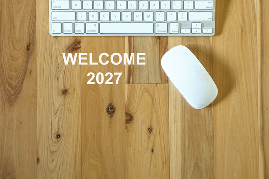 Welcome new year 2027 - message next to computer mouse and keyboard. Top view.