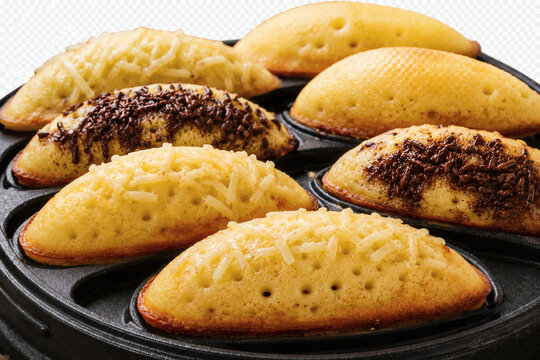 Freshly baked traditional Indonesian sponge cake called kue cubit or pukis with various toppings like cheese and chocolate sprinkles on a pan