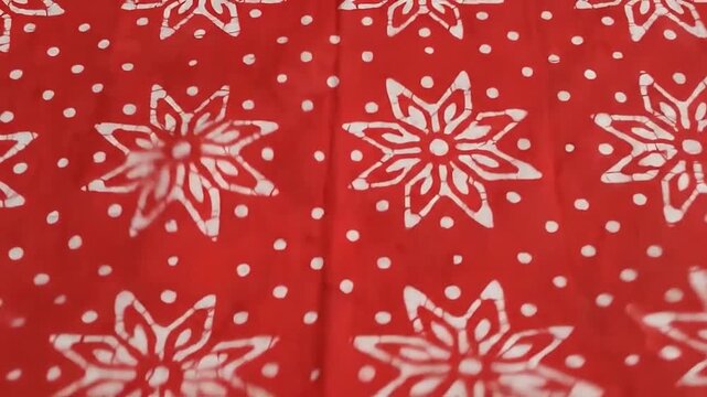 Traditional Indonesian red batik fabric with white floral pattern panning slowly