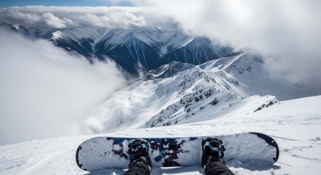 A person sits on a snowboard atop a snowy mountain ridge. The individual is positioned with their legs extended, wearing snowboarding boots and gloves.
