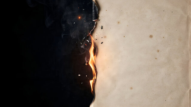 Burning edge of an old vintage paper sheet with smoke and flames on a dark background