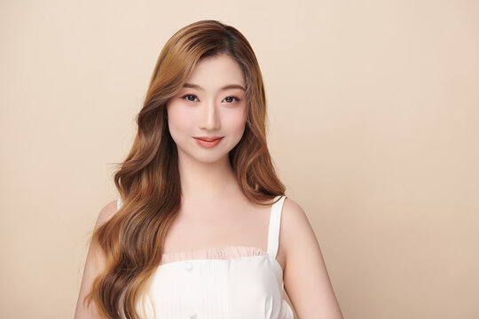 A beautiful young Asian woman with clean, fresh skin against a beige background. Skincare, facial treatment, cosmetology, beauty, and spa. An elegant portrait of an Asian woman.