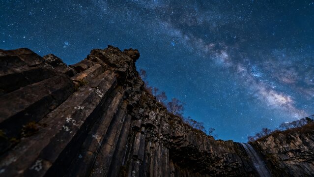 Star-filled night sky above basalt columns and rocky cliffs