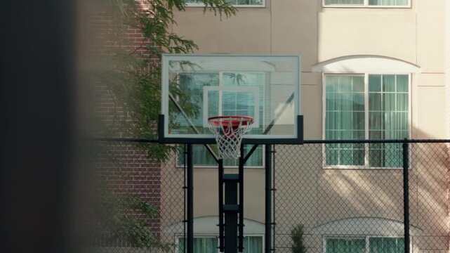 Camera glides left to right, revealing a hoop in front of a chain-link fence.