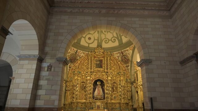 Tilt down shot of ornate golden baroque altarpiece and virgin mary statue in church