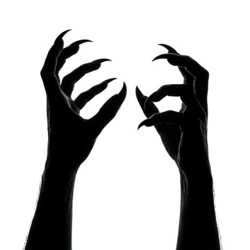 Black silhouette of scary monster hands with long sharp claws reaching up