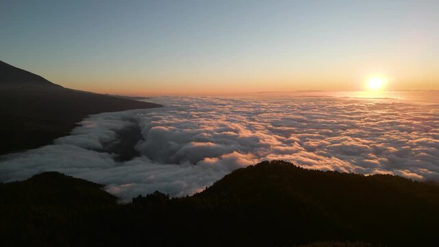 Sunrise over a sea of clouds with mountain silhouettes at Teide viewpoint, Tenerife