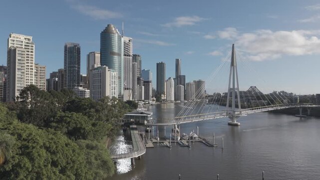 An aerial view shows the Kangaroo Point Bridge and a riverside pontoon building beside the Brisbane CBD skyline.