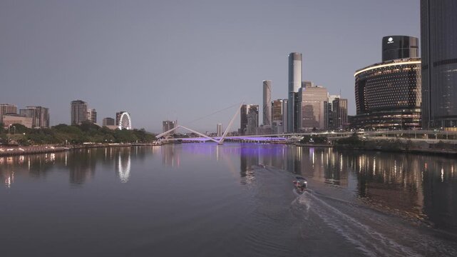 An aerial view shows the Neville Bonner Bridge and the ring topped city tower reflected in the river at dusk.