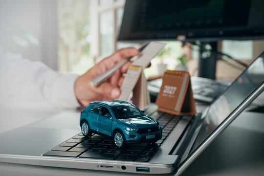 Business professional planning timeline and calculating vehicle-related expenses, car model, laptop keyboard with 2027 calendar, auto loan concept, car insurance, vehicle financing, purchase planning.