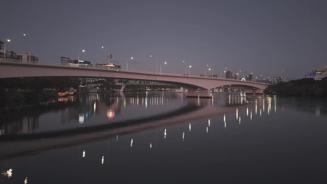 An aerial view glides alongside the Captain Cook Bridge over the Brisbane River at dusk.