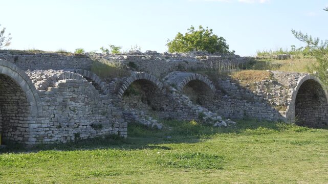 Berat Castle stone arch vaults and ruined walls above green grass in Albania