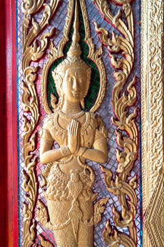 Decorative golden Thai angel relief sculpture adorned with colorful glass mosaic tiles.
