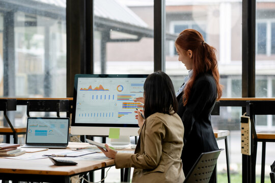 Business women collaborating on a project, analyzing data and financial reports on computer screen