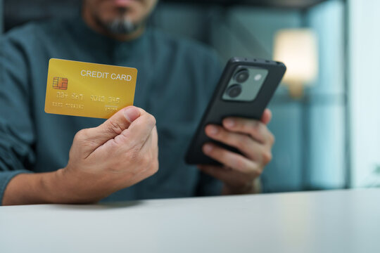 Asian Man holds a credit card and smartphone for online payment authentication, representing identity verification, mobile banking, transaction security, privacy protection.