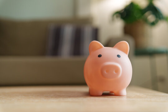 Pink piggybank on a wooden table with copy space in a cozy home
