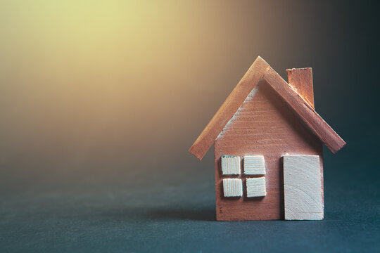 Miniature wooden house on black background with copy space for your text