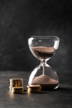 Time is money concept hourglass with falling sand and stacks of coins financial planning investment growth and economic deadline pressure