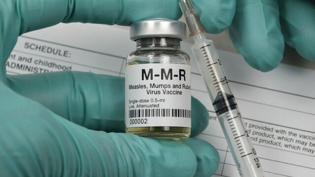 Healthcare professional wearing green medical gloves holding an mmr vaccine vial and filled syringe with medicine
