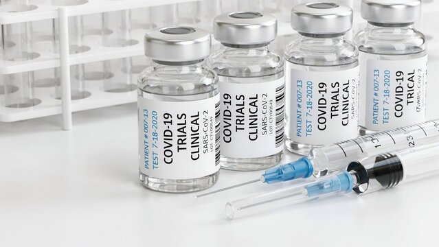 Close-up of covid-19 clinical trial vaccine vials in a row with medical syringes on a white laboratory table