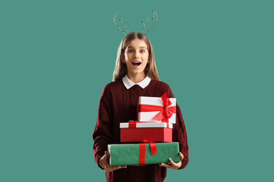 Surprised teenage girl with Christmas gifts on green background