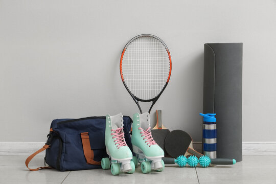 Different sports equipment, bag and roller skates near light wall