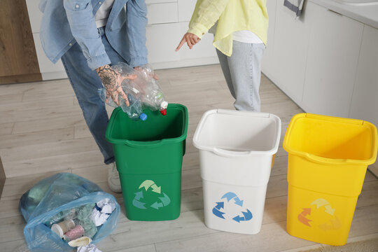 Young couple with garbage containers sorting rubbish in kitchen. Recycling concept