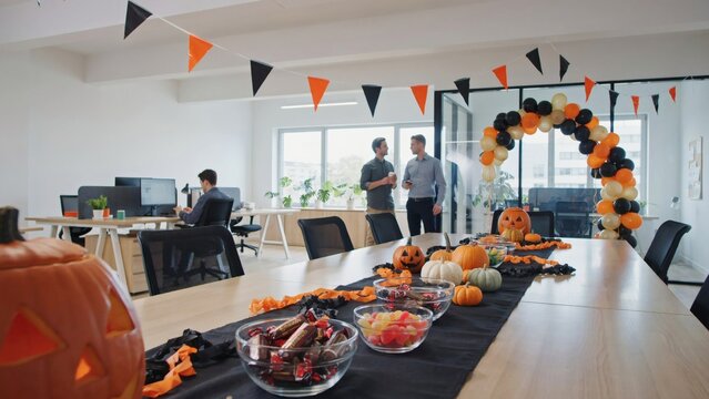 Halloween office party table with pumpkins candy and balloon arch