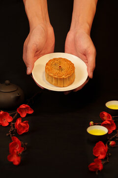 Hands holding plate with traditional mooncake for Mid-Autumn Festival celebration