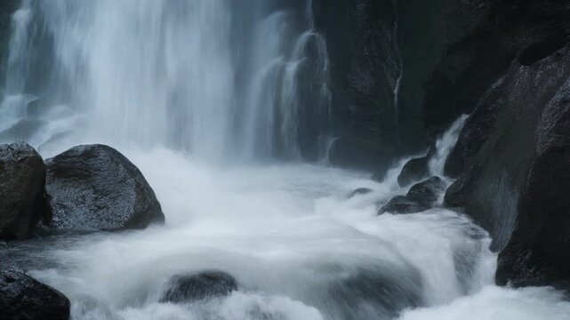 Yosemite falls flowing over dark wet rocks in nature