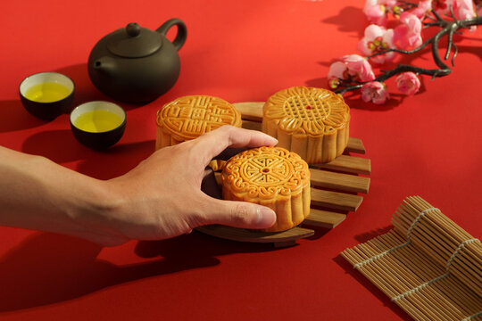 Cropped hand reaching for traditional mooncake for Mid-Autumn Festival celebration