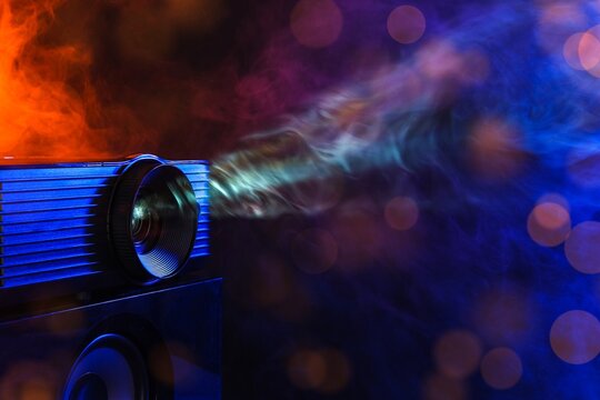 Cinema and entertainment technology, digital projector casting light beam with smoke and atmospheric bokeh effects in a dark room for movie screening