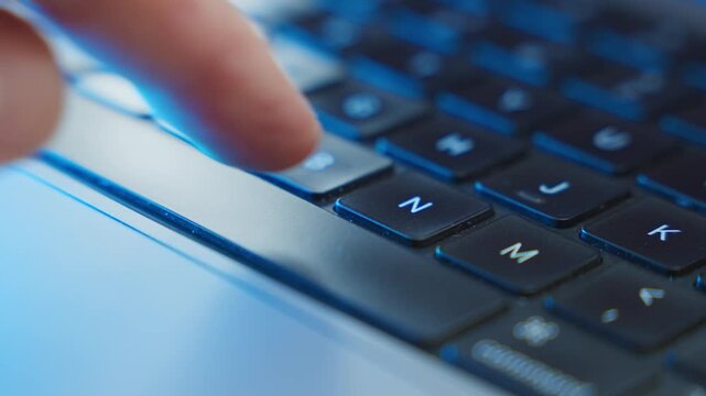 Close up on finger pressing the space bar key on laptop computer keyboard in dark office room. Mysterious atmosphere cyber hacker or criminal or programmer clicking button to start process algorithm