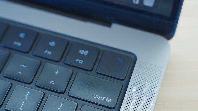 Person's thumb pressing on fingerprint scanner on laptop computer to access system or to confirm operation. Identifying user by clicking on key with ID reader for thumbprint. Close up in office desk