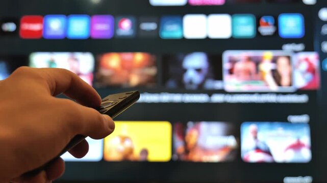 Person Holding Remote Control and Choosing Movies on Modern Smart Television
