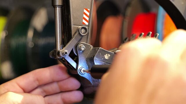 Close-up of male hands using a precision electric screwdriver to replace the dirty bucket on a radio-controlled toy excavator arm.