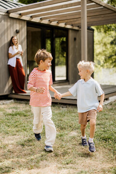 Children play joyfully in the sun near a cozy modern home