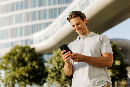 Smiling man enjoys smartphone in modern urban landscape