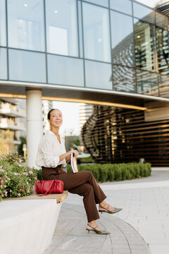 Korean woman enjoying a sunny day at an urban plaza while reading a book