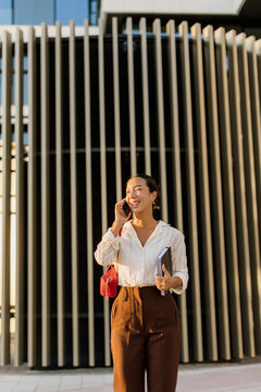 Korean woman smiles while talking on her phone in a modern urban setting