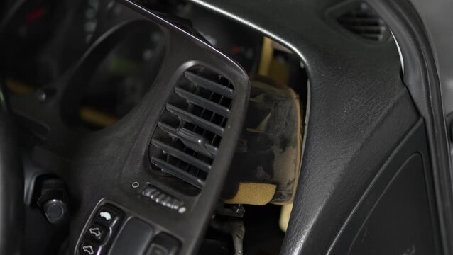 Car dashboard trim panel with air vent removed for repair.