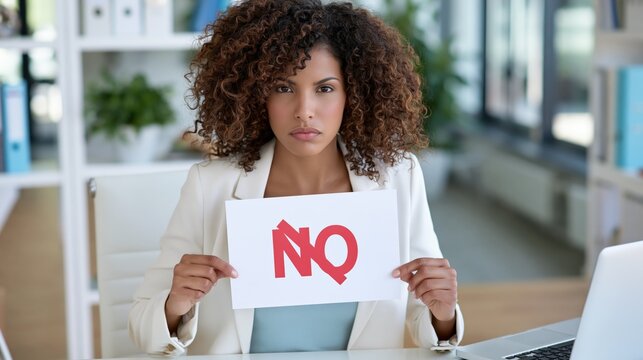 Woman with an unhappy expression holds up a sign with the word NO written on it.