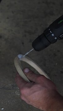 Man holding a custom plywood car speaker spacer ring near drill.