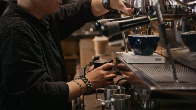 Young adult barista wiping steam wand, taking espresso cup and pouring steamed milk to make latte art. Footage ideal for coffee shop marketing, beverage advertising and barista training