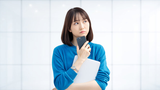 スマートフォンとノートパソコンを持って考える女性・ビジネスウーマン, Businesswoman Thinking While Holding a Smartphone and Laptop