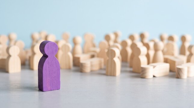 Purple wooden figure standing out from crowd of natural wood figures on light background, leadership and individuality concept in human resources management