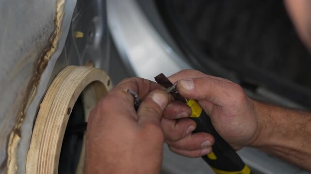 Man hands using utility knife to strip car speaker wire.