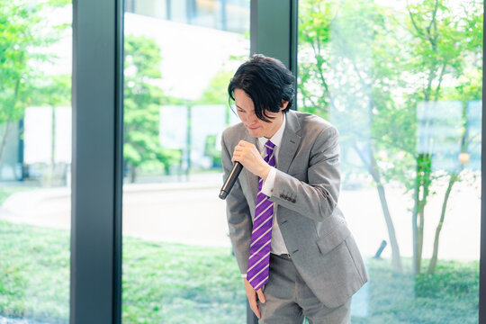 にこやかにマイクで話す男性のビジネスマン