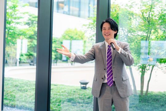 にこやかにマイクで話す男性のビジネスマン