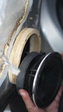 Man hands fitting acoustic speaker into custom plywood adapter ring.